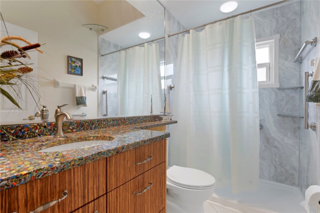 Modern bathroom with wooden cabinetry and granite countertop.