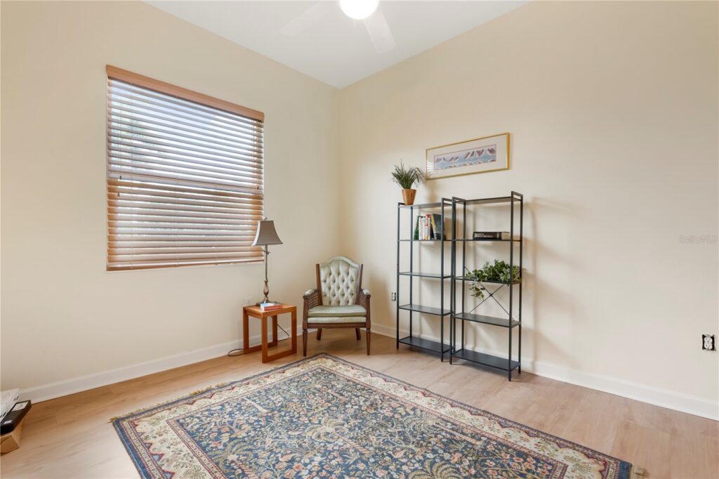 A cozy corner with a chair, plants, and a decorative rug in a softly lit room.