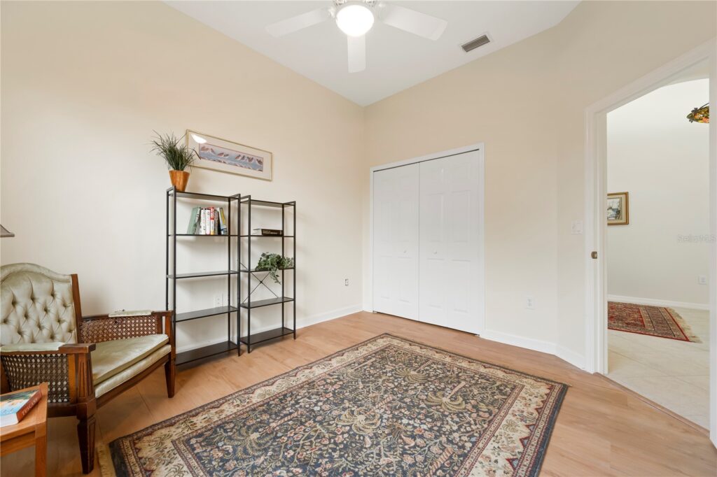 Minimalist room with a large rug, shelving unit, and chair under soft lighting.