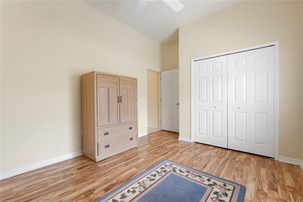 Empty bedroom with wooden floor and white closet doors.