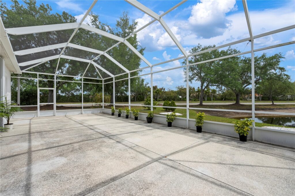 Empty screened patio with potted plants under a blue sky.
