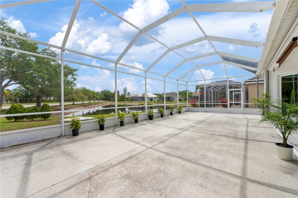 Spacious screened patio with potted plants and clear blue sky.