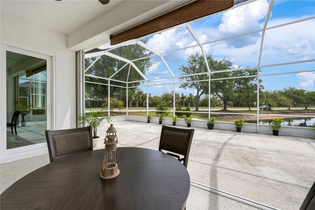 Modern patio dining area with screened enclosure and scenic view.