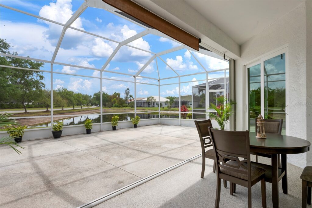 Spacious screened patio with outdoor dining set and clear sky.