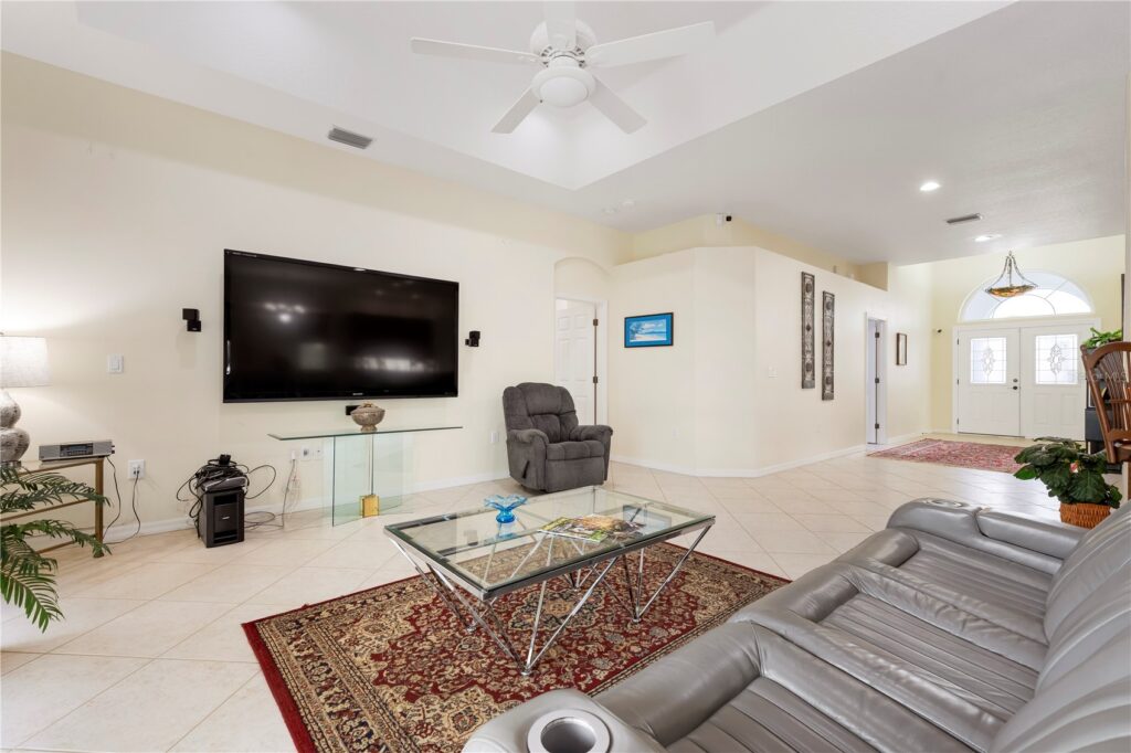 Modern living room with TV, recliner, and glass coffee table on a patterned rug.