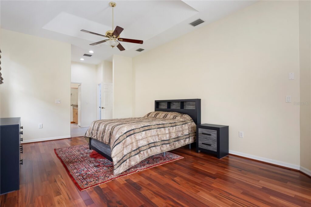 Minimalist bedroom with wooden floors and ceiling fan.