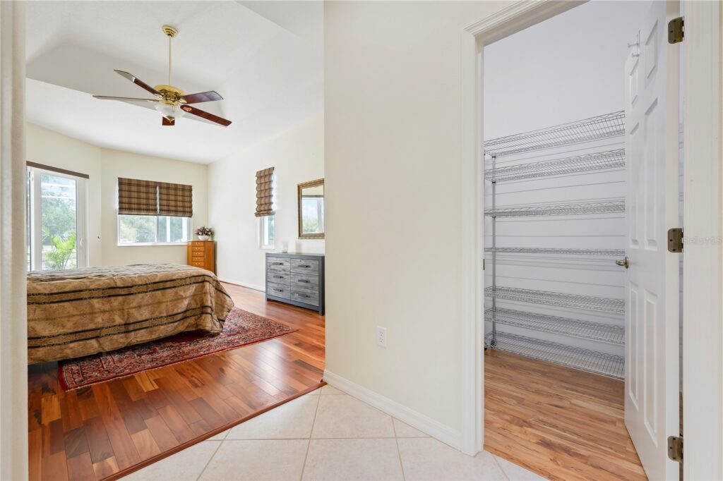 Bright bedroom with wooden floors and adjacent empty closet.