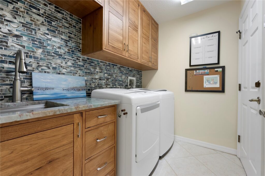 Modern laundry room with washer, dryer, and wooden cabinets.