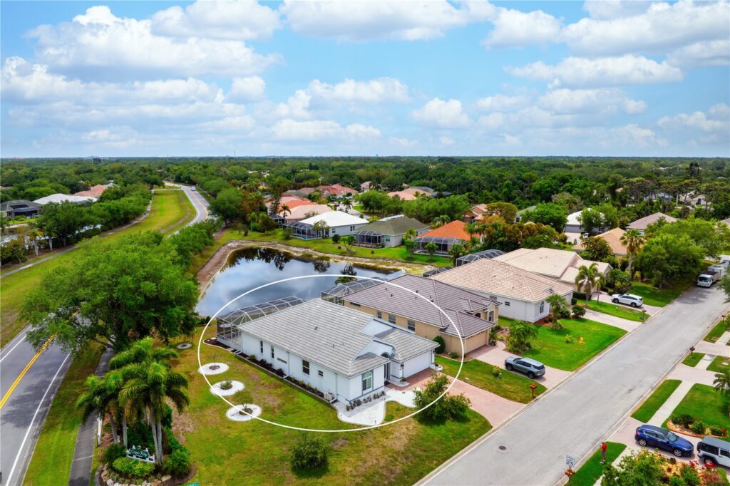 Aerial view of suburban homes with solar panels under a partly cloudy sky.