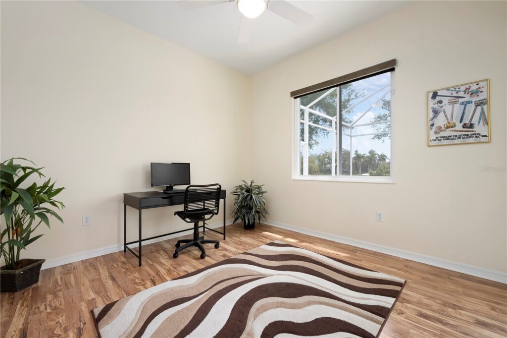 Minimalist home office with a desk, computer, and patterned rug.
