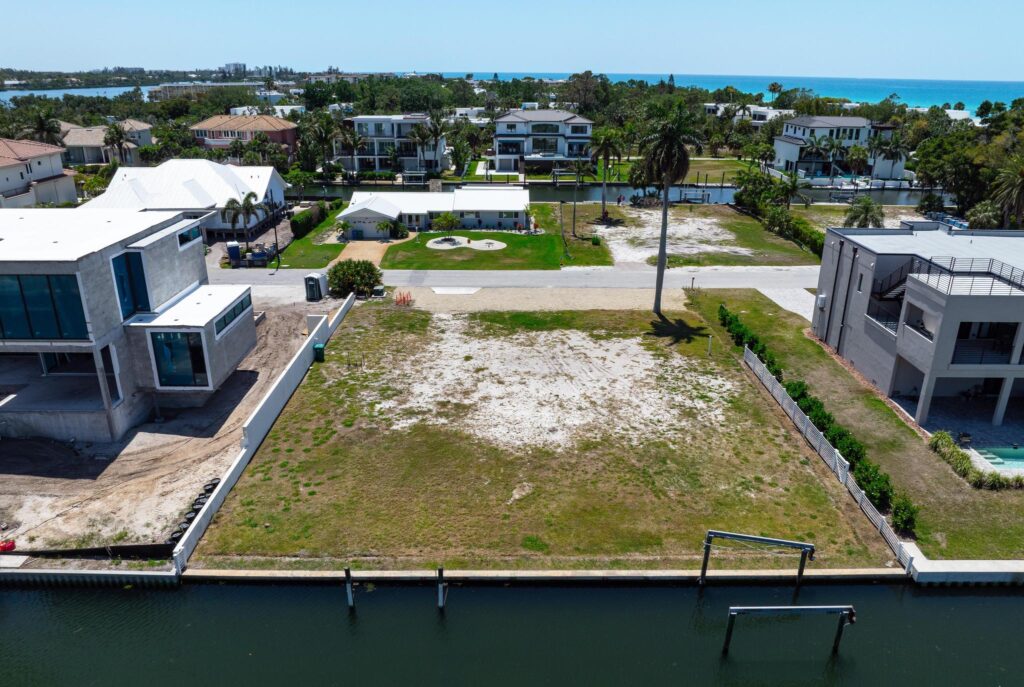Empty waterfront lot with grass and sandy patches.