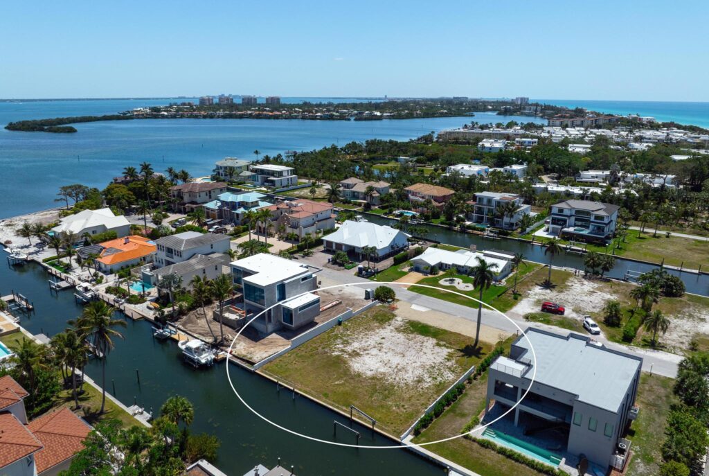 Aerial view of waterfront homes along a canal with a large river in the background.