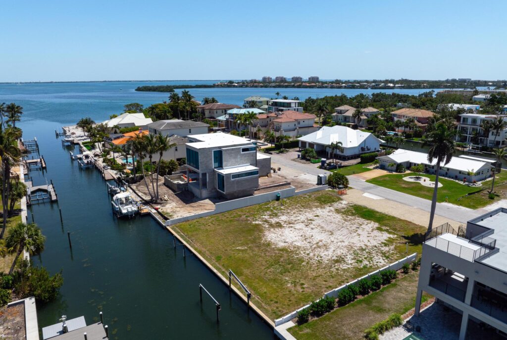 Aerial view of waterfront homes with a vacant lot near a canal.