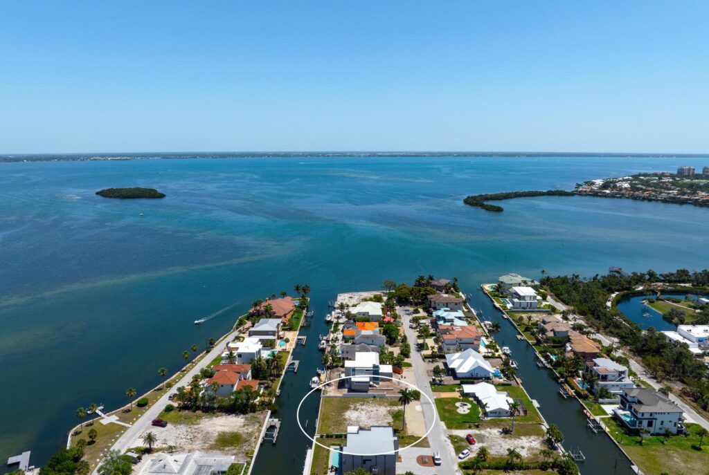 Aerial view of waterfront homes along a canal opening to the ocean.