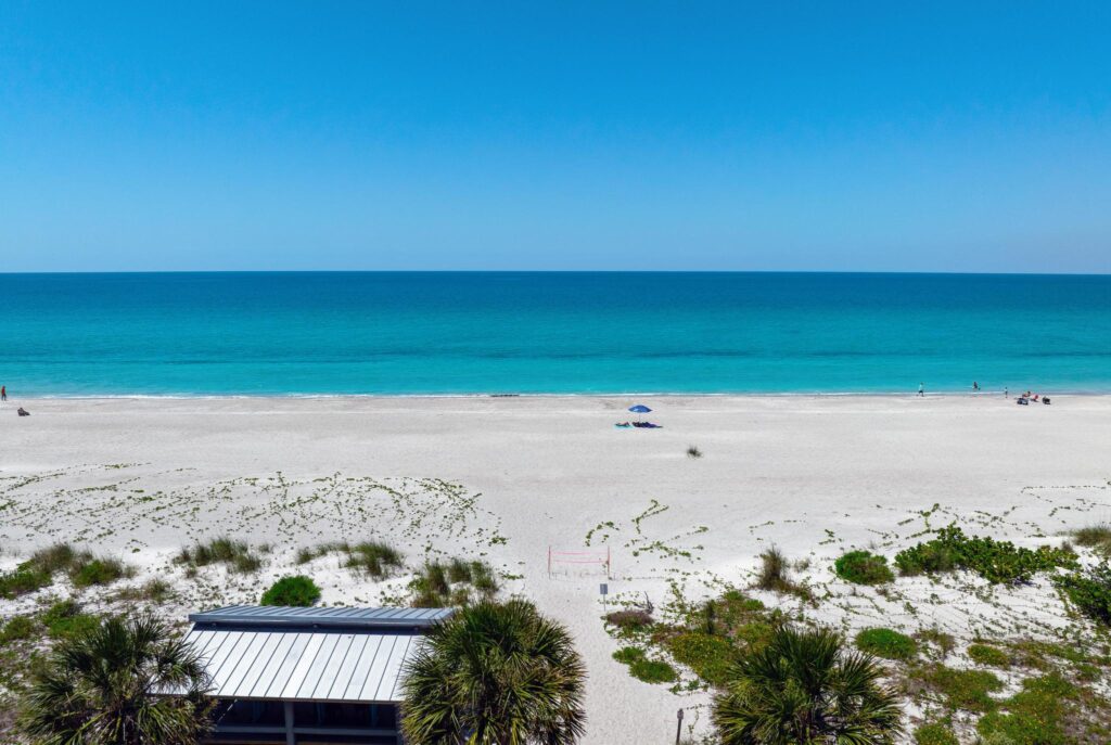 Sunny beach with clear blue sky and calm ocean waves.