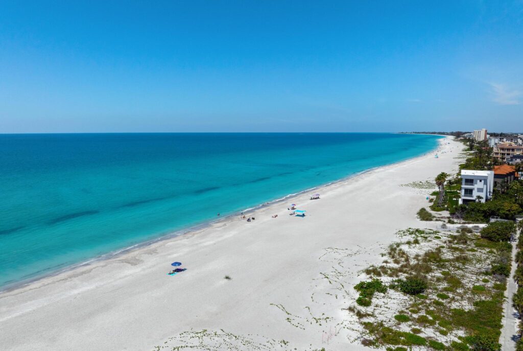 A serene beach with white sand and turquoise water under a clear blue sky.