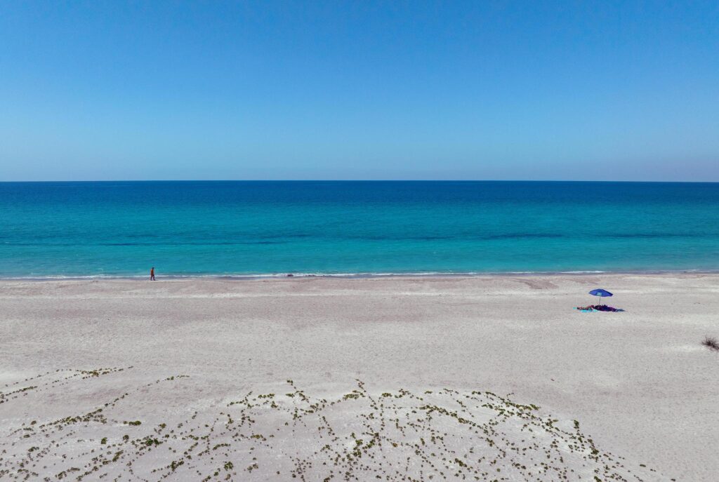 A serene beach with clear blue sky and calm turquoise sea.