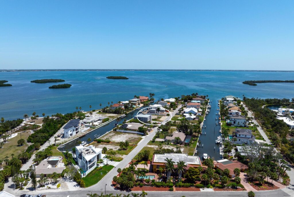 Aerial view of a coastal residential area with waterways and boats under a clear blue sky.