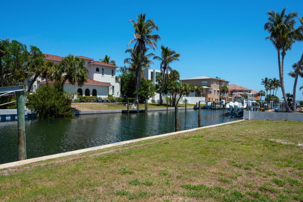Canal with palm trees and houses under a clear blue sky.
