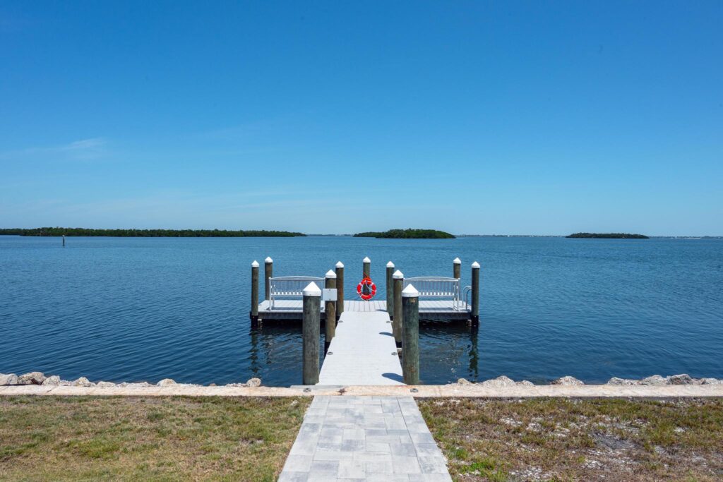 Pier stretches into calm blue water under clear sky.