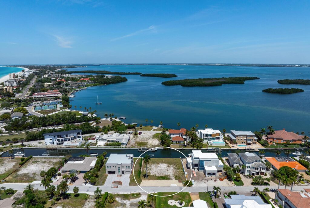 A coastal city with buildings along a blue bay and islands.