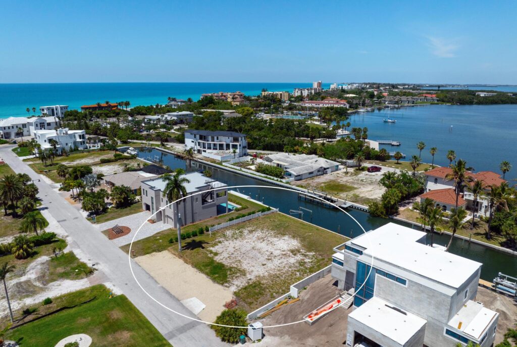 Coastal neighborhood with waterways and modern houses under a clear blue sky.